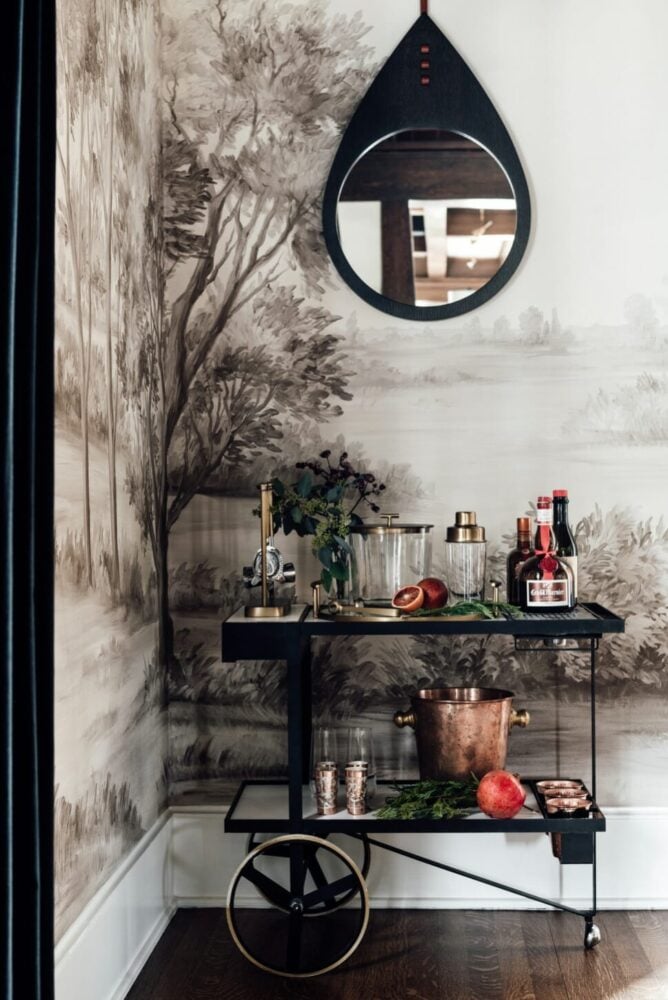 Mid century bar card with blood oranges and copper items in front of a brown painted landscape mural on the walls
